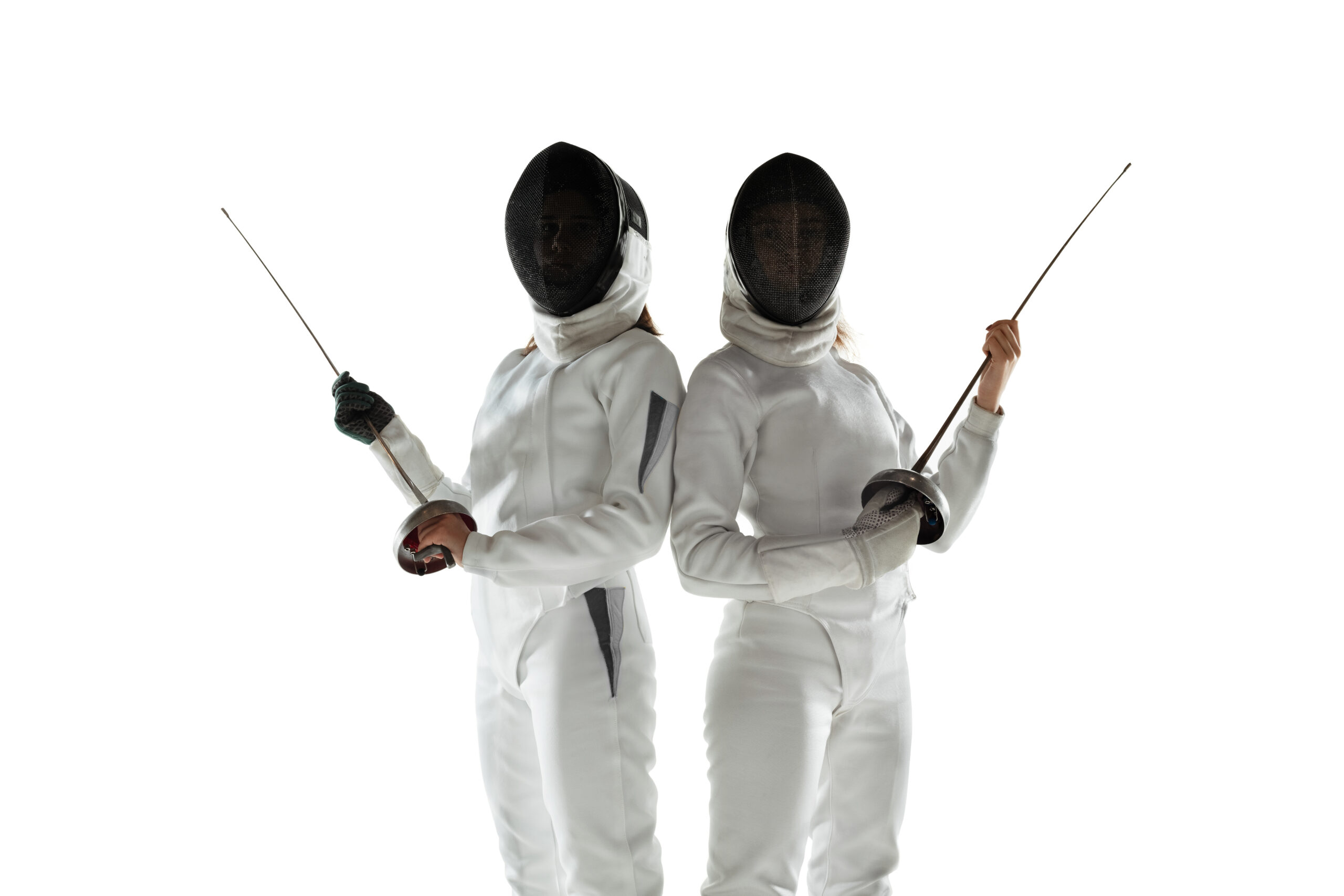 Teen girls in fencing costumes with swords in hands isolated on white background